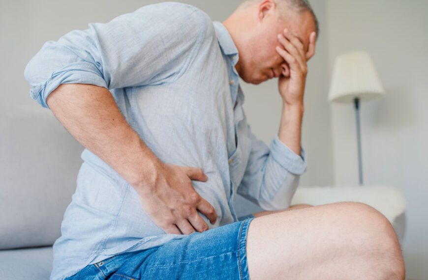 man holds side of stomach in pain