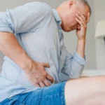 man holds side of stomach in pain