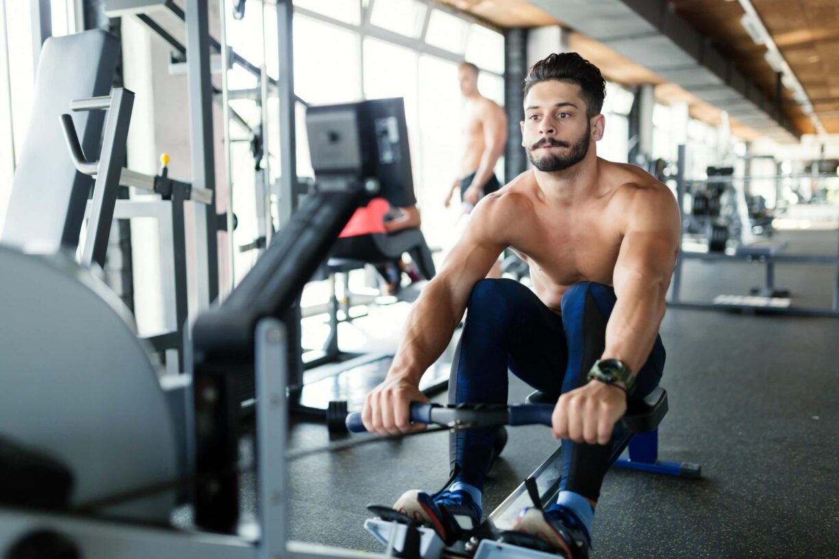 man on indoor rowing machine in gym