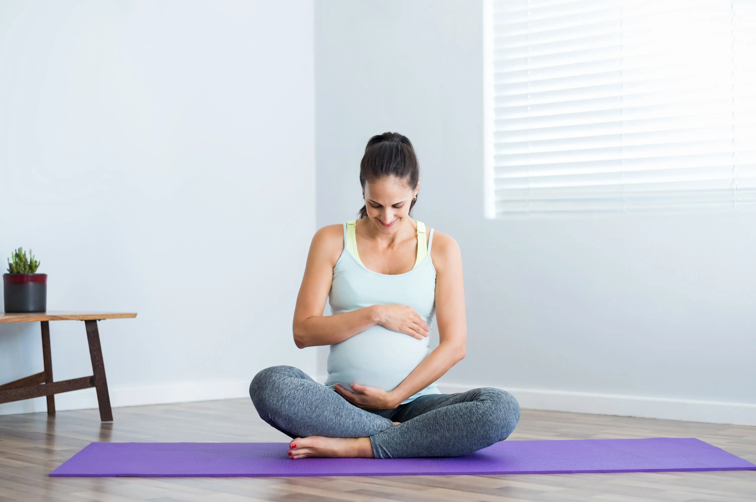 Pregnant woman sitting on yoga mat scaled