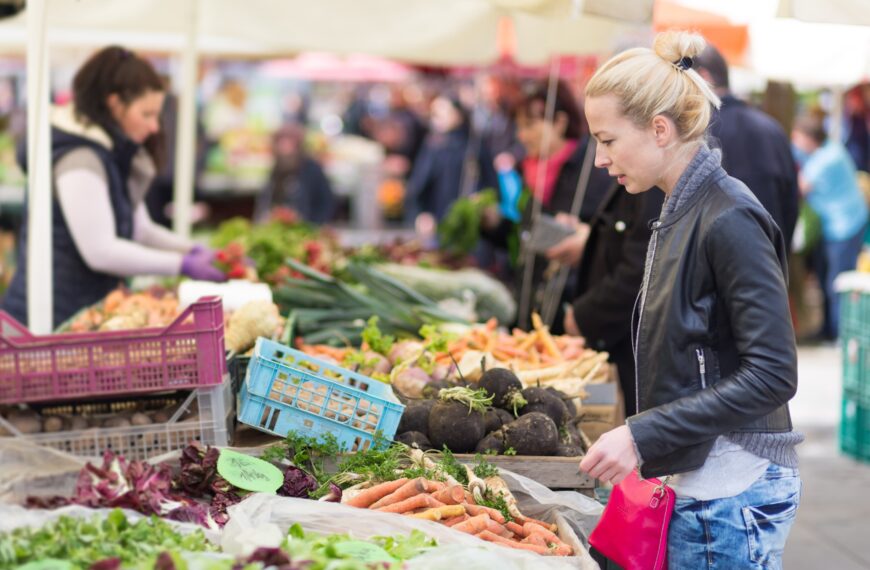 woman looks at vegetables on market stall