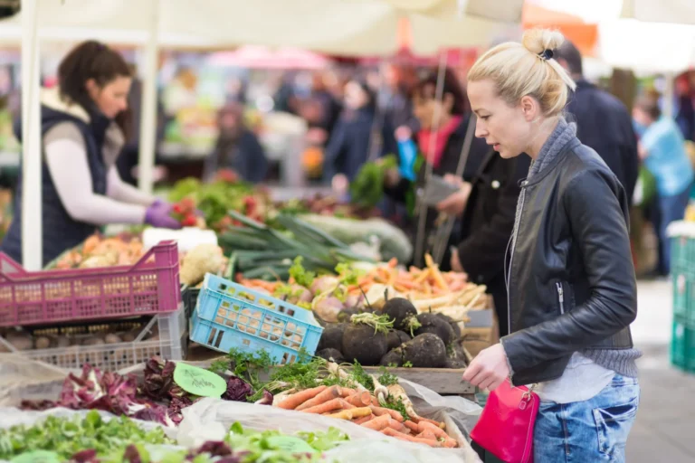 woman looks at vegetables on market stall