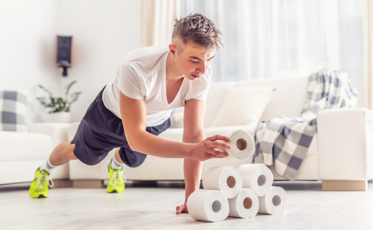 young man holding a plank whilst stacking toilet roll