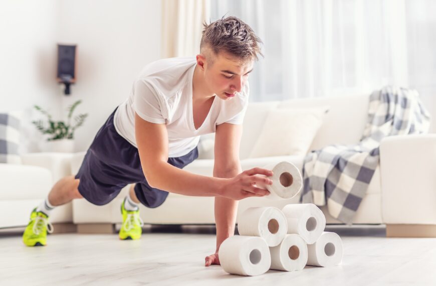 young man holding a plank whilst stacking toilet roll scaled