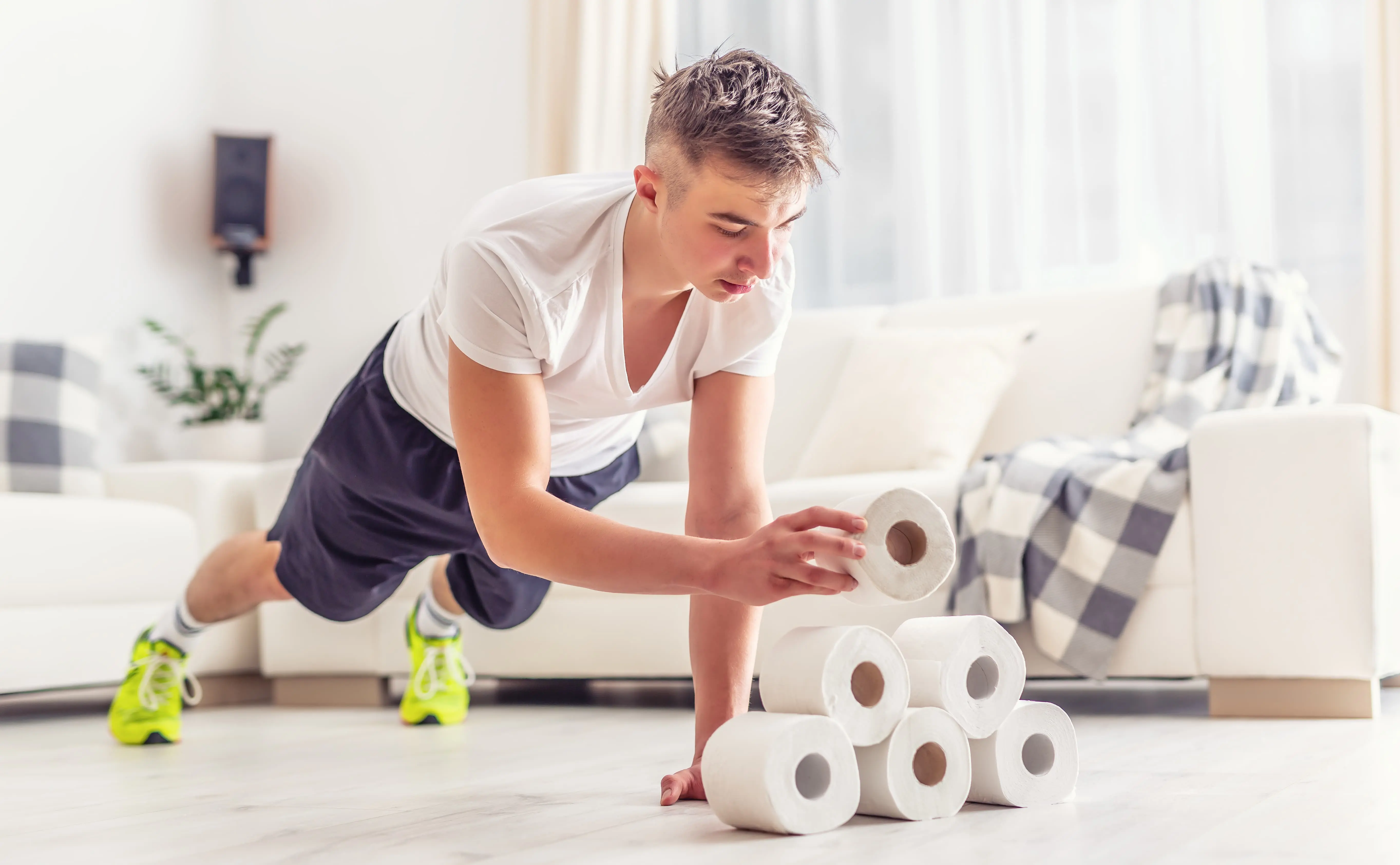 Young man holding a plank whilst stacking toilet roll scaled