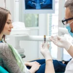 Male dentist showing his female patient a dental implant
