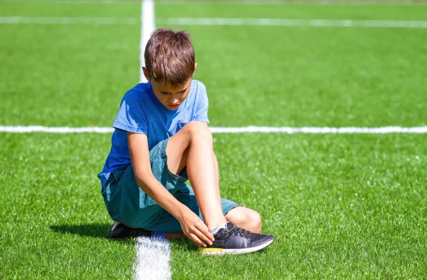 child sits in pain looking at ankle scaled