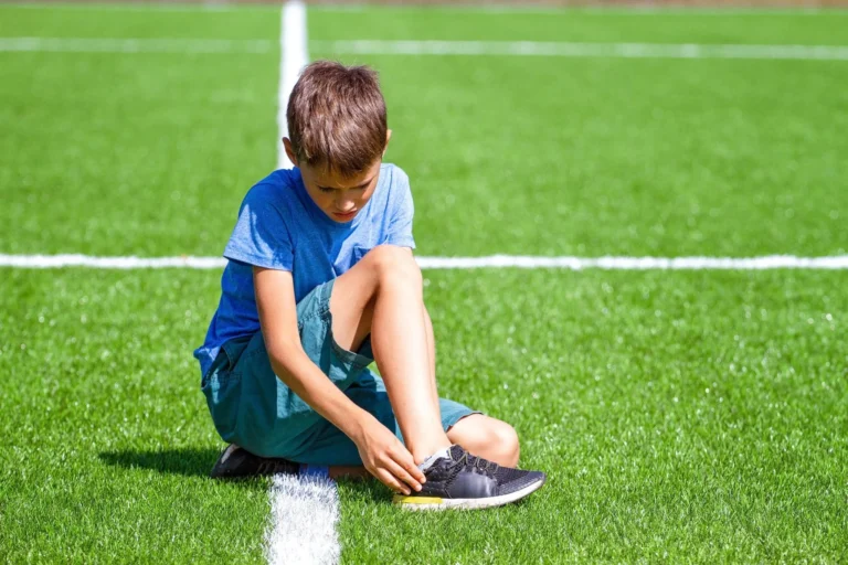 child sits in pain looking at ankle scaled