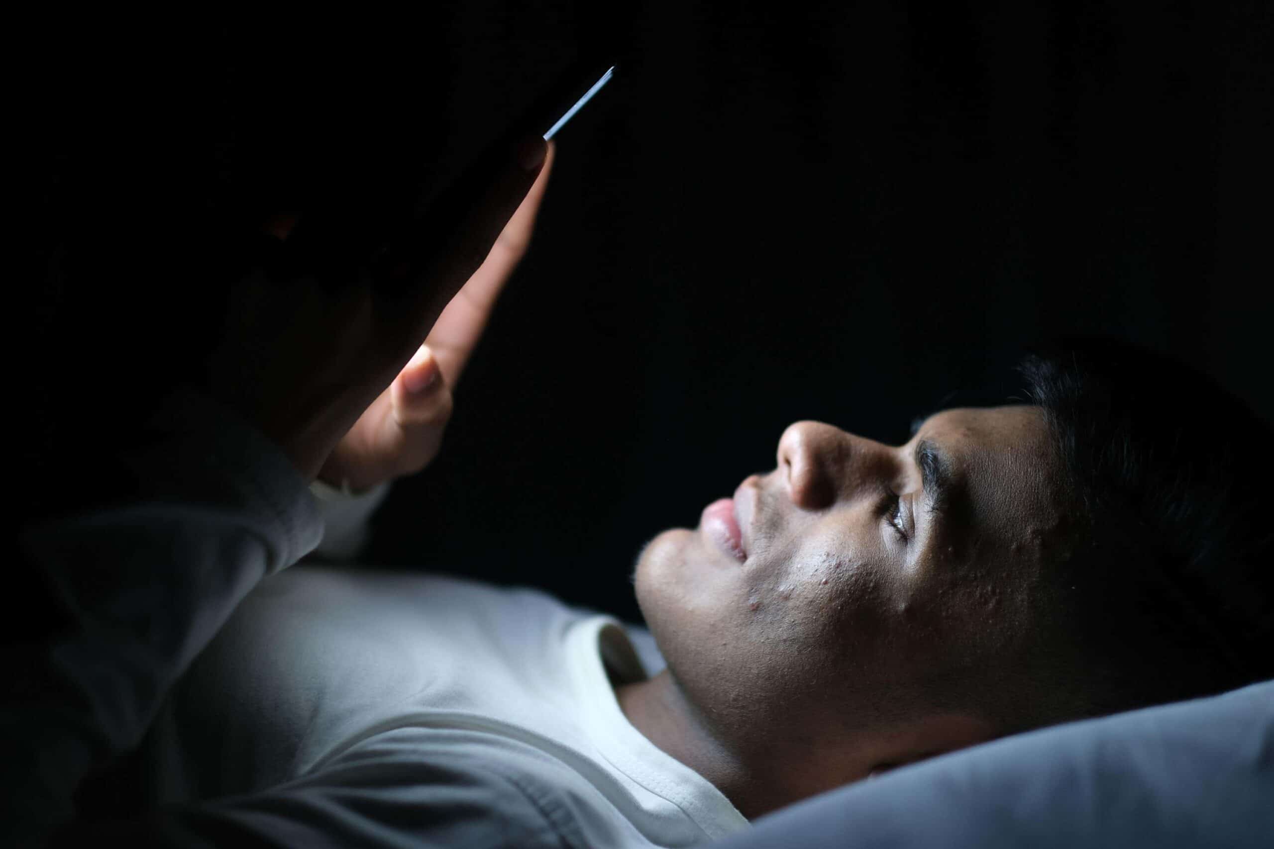 Man checks phone in bed scaled