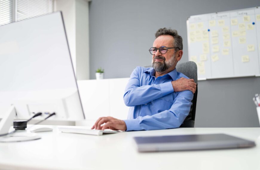 office worker holds shoulder in pain