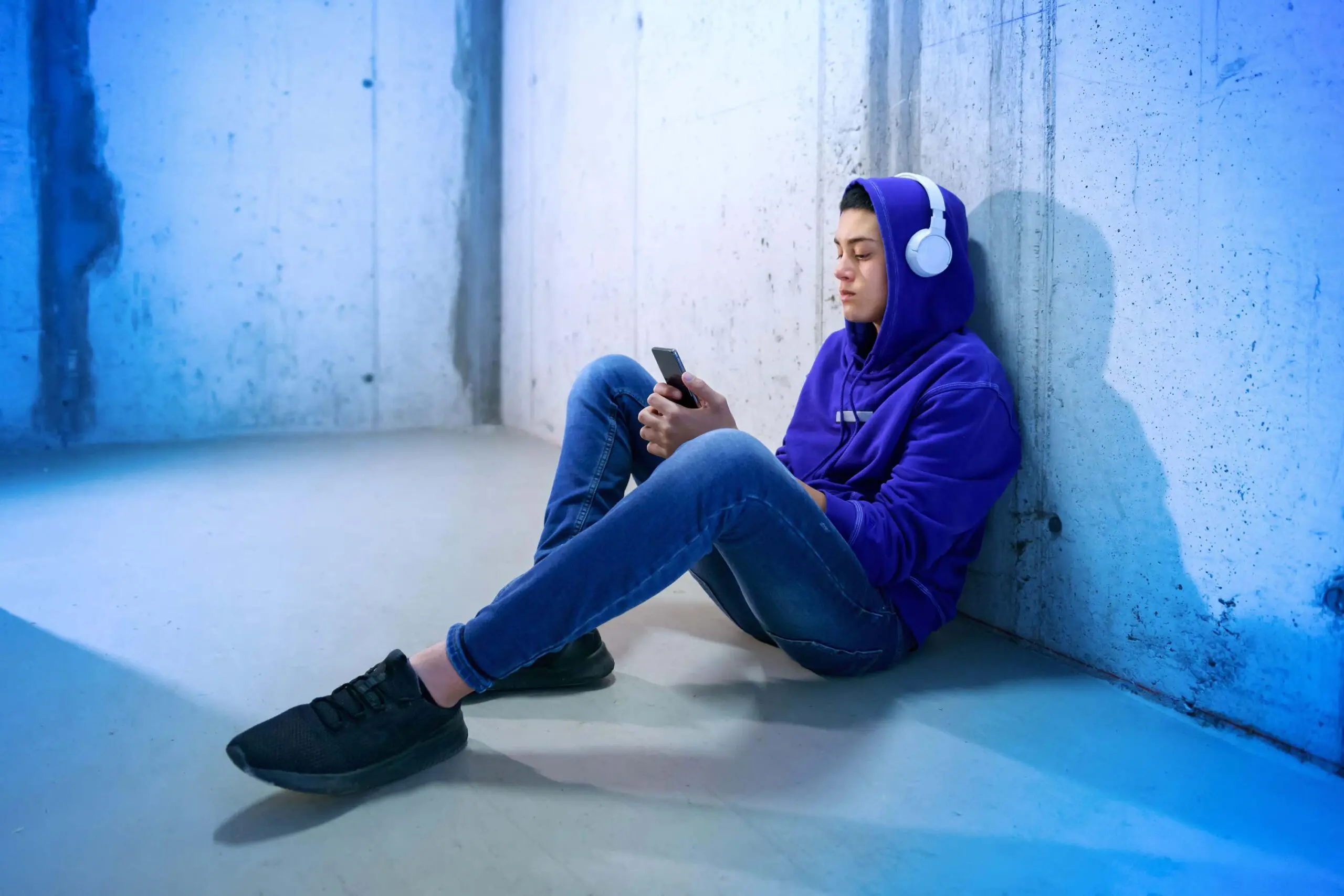 Teen sits wearing headphones scaled