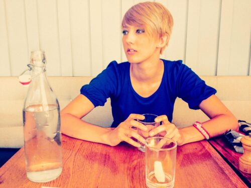 woman sits at table with drink scaled