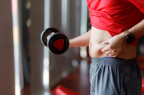 fitness goer pinches belly fat