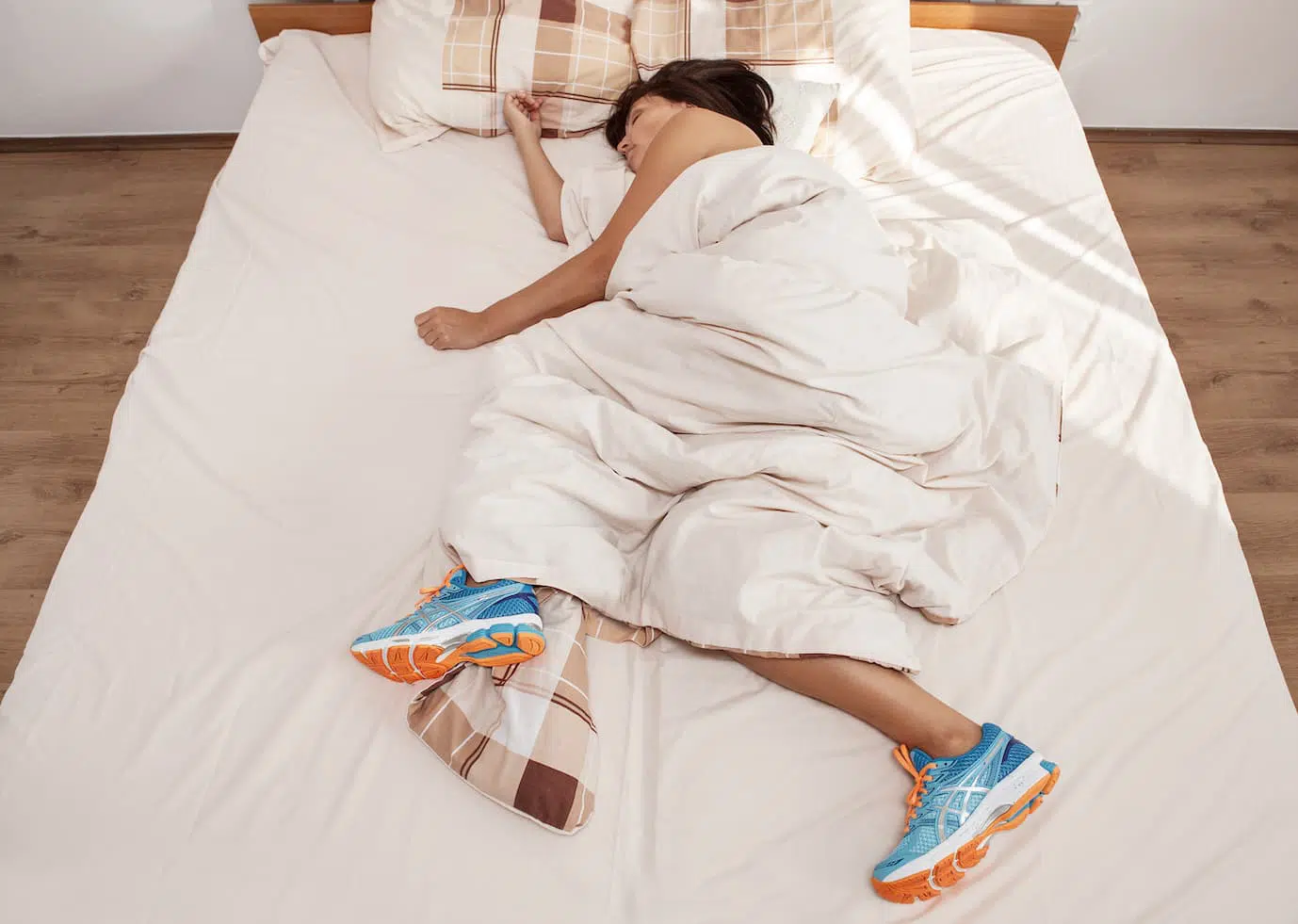 Person asleep with running shoes in bed