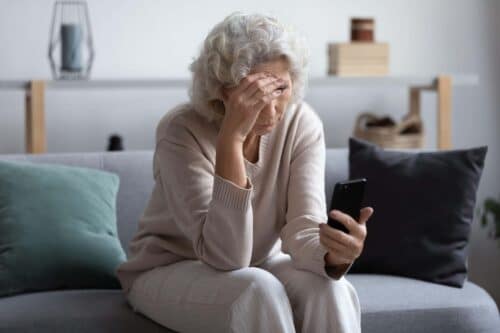 woman looks stressed at her phone scaled