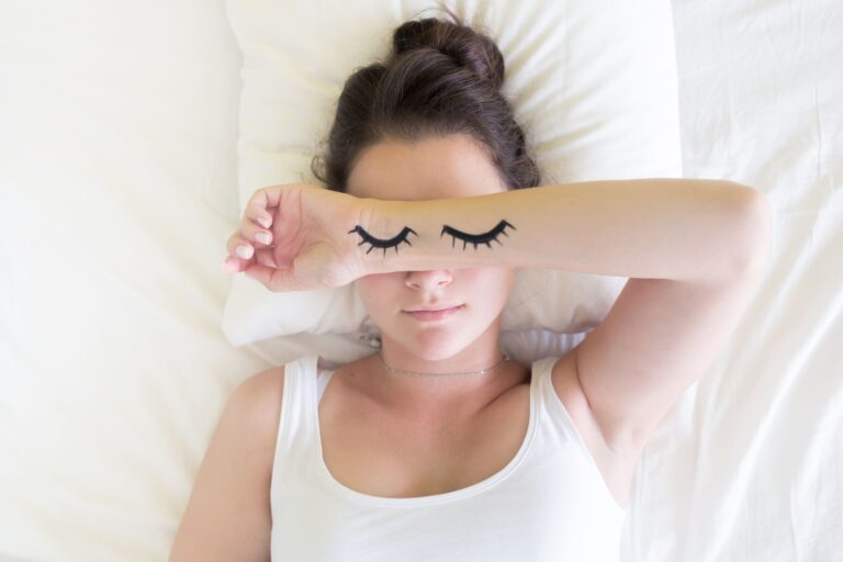 woman sleeps with eyes drawn on arm