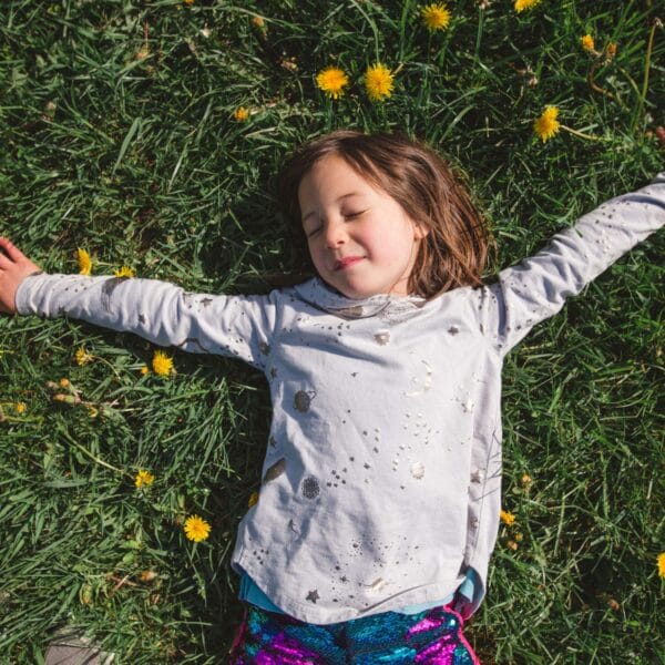 child lays on grass amongst the daisys scaled