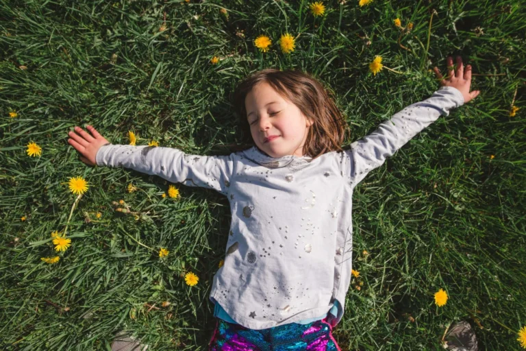 child lays on grass amongst the daisys scaled