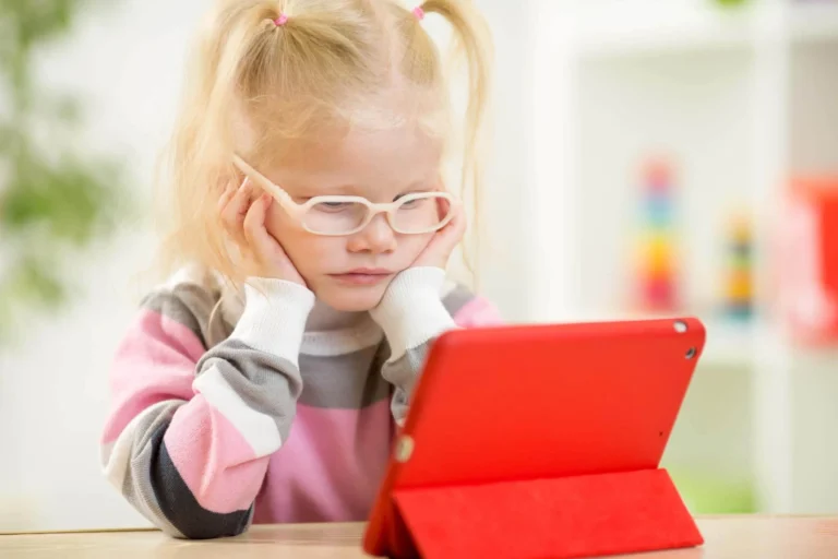 child wearing glasses watches tablet