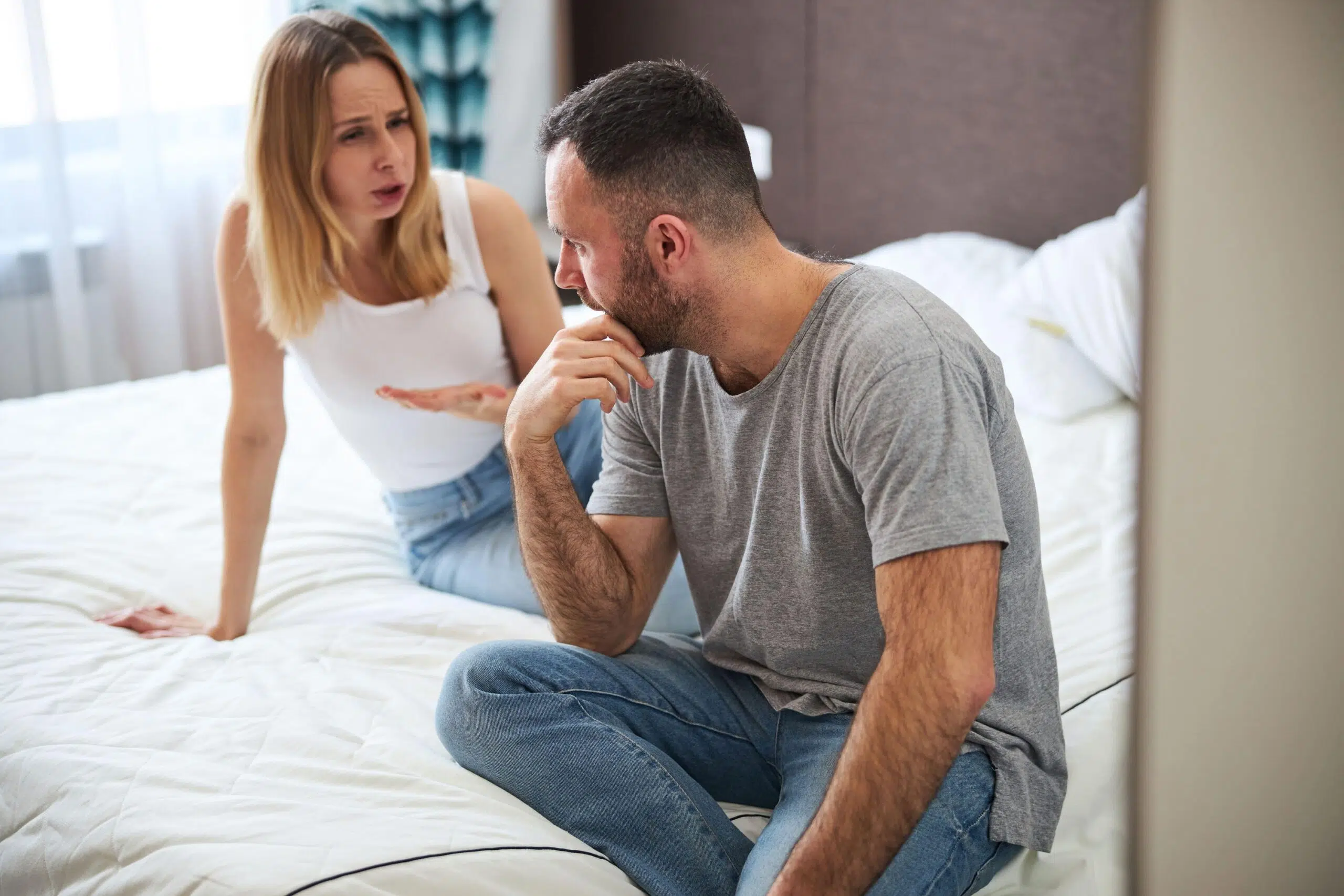 Couple looking stressed out on bed scaled