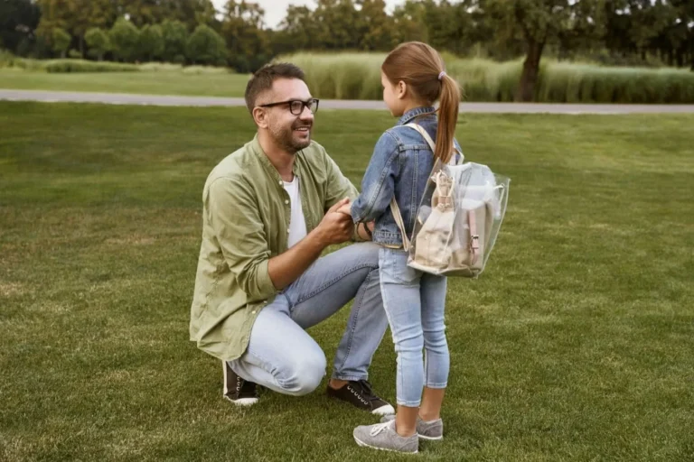 father kneels and smiles at daughter scaled e1629563547575