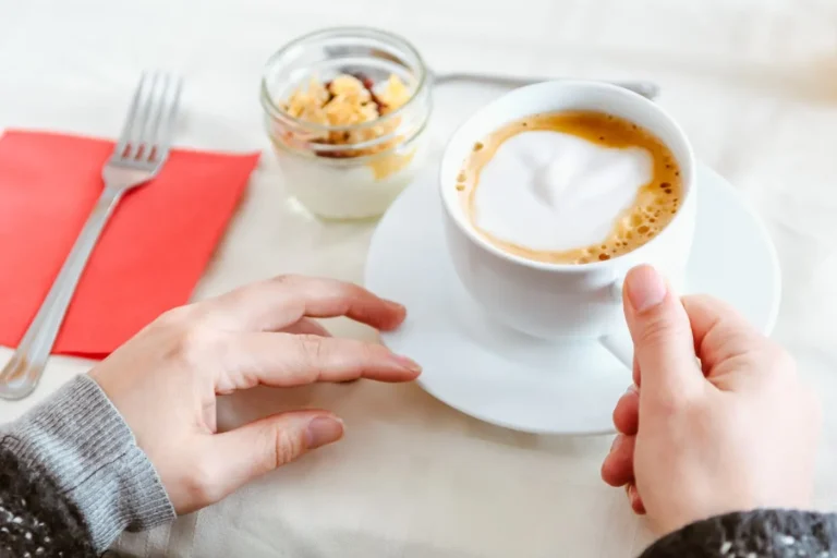 person holding white ceramic cup with cappuccino scopio f482e205 5946 4b93 95b8 fdd3e5381dfd