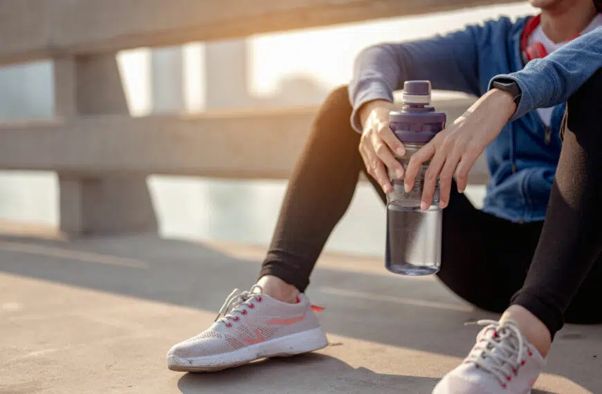 runner sits holding water bottle for hydration