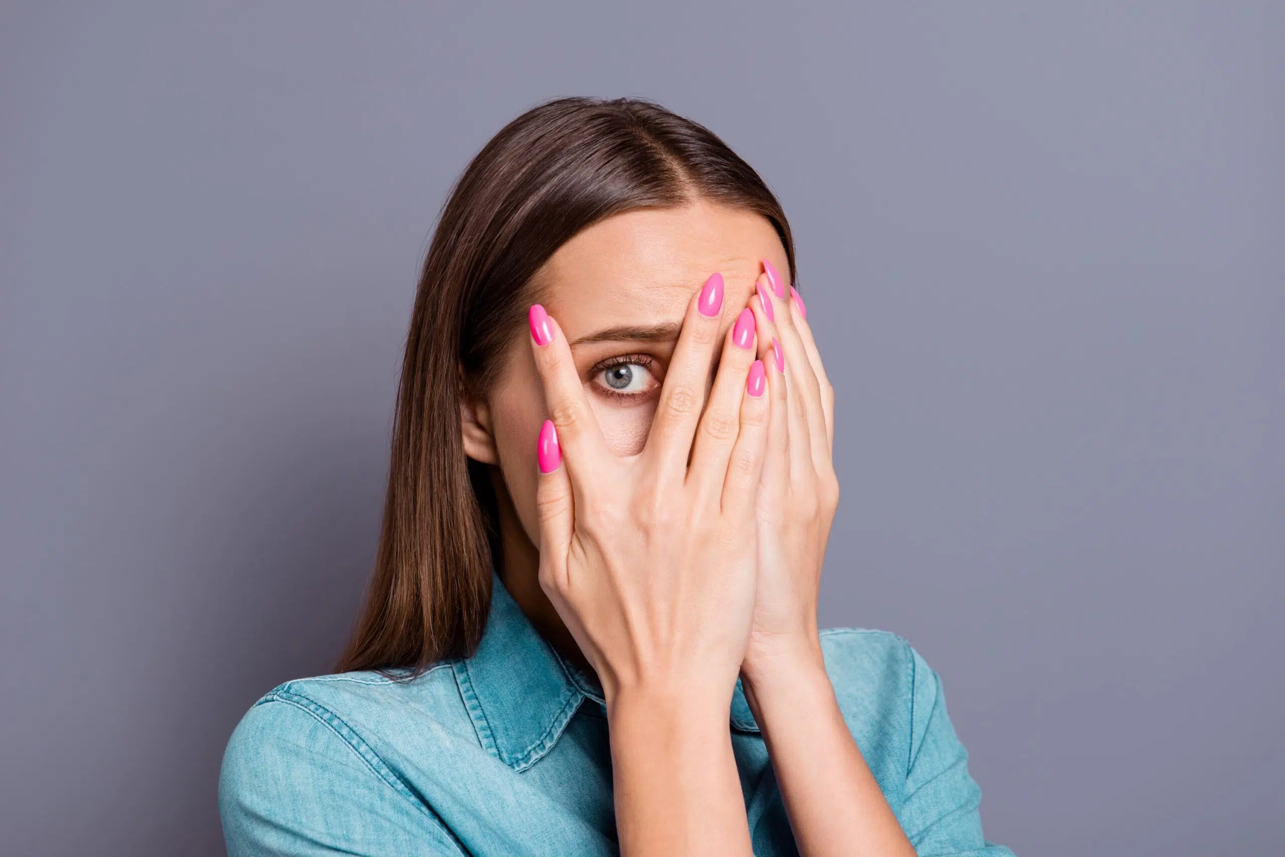 Woman hides behind hands scaled