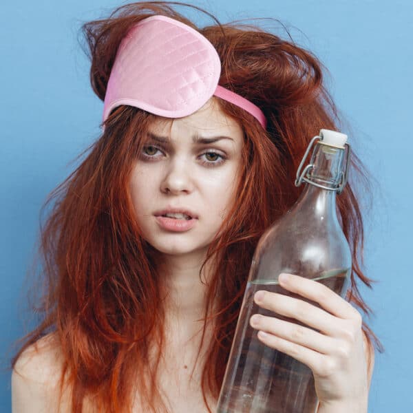woman holds bottle looking tired