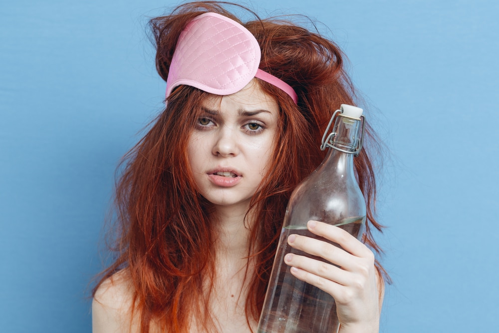 Woman holds bottle looking tired