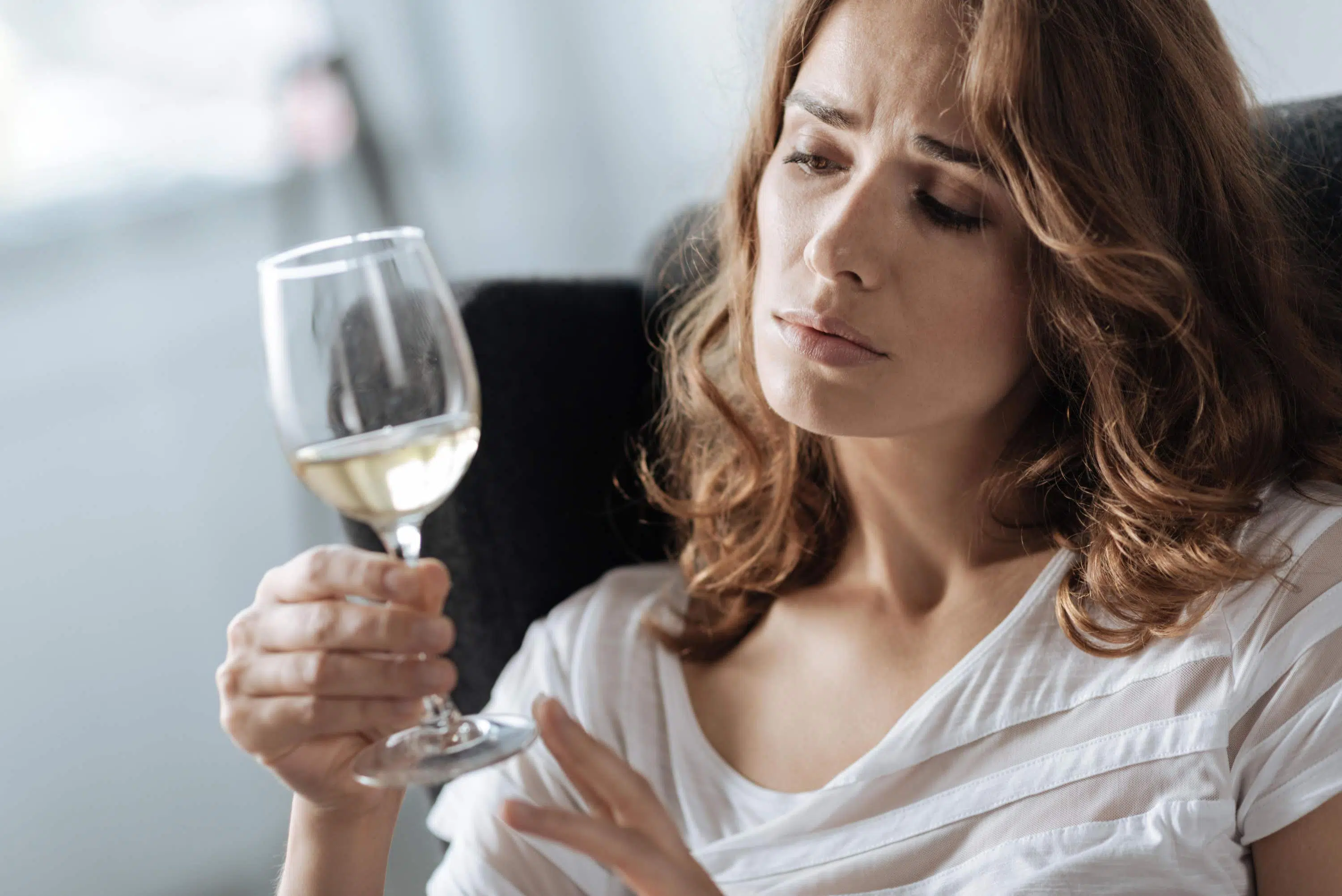 Woman stairs despairingly at wine glass scaled e1629562504875