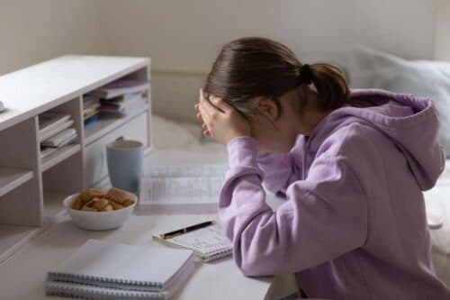young girl looks stressed over her desk scaled
