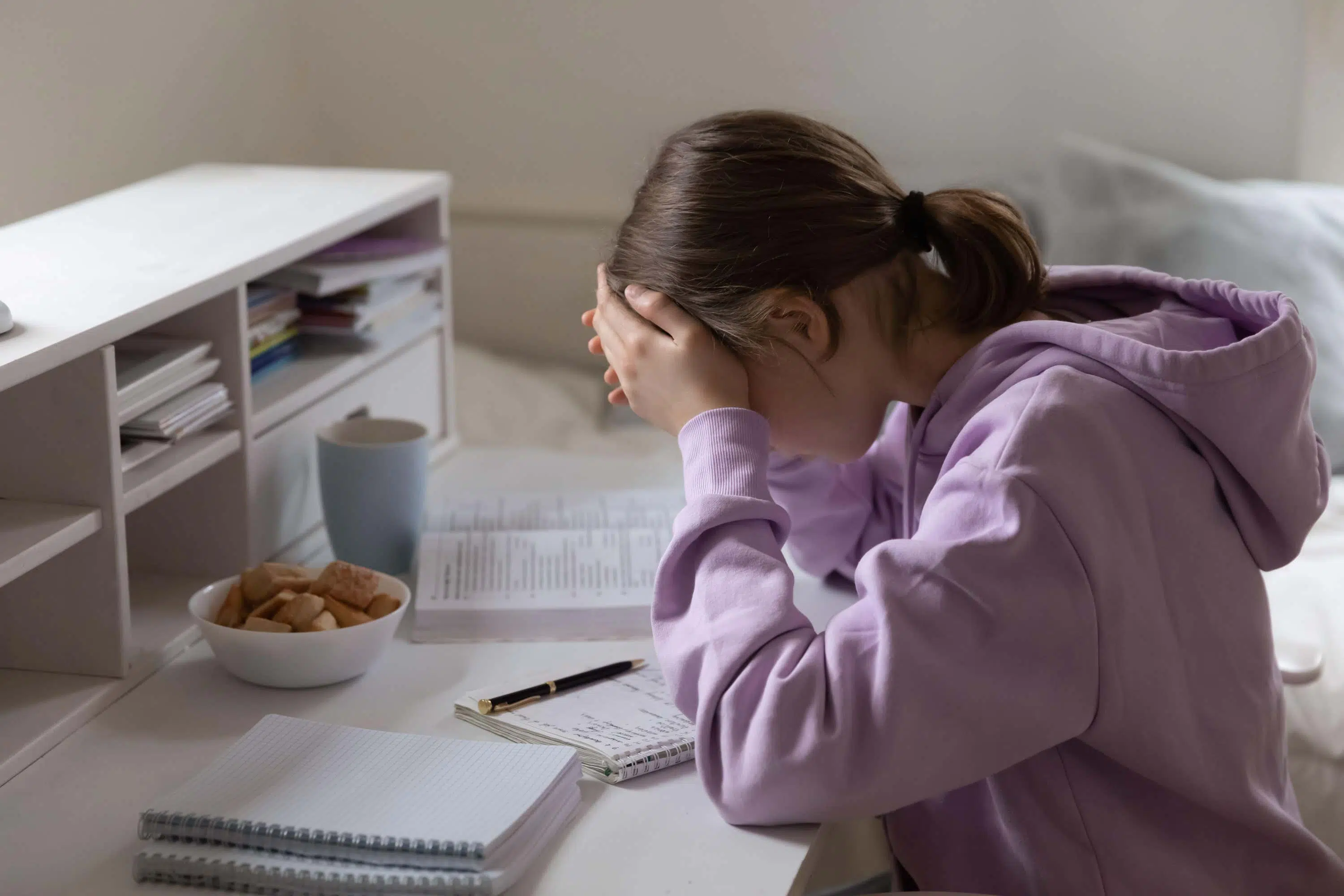 Young girl looks stressed over her desk scaled