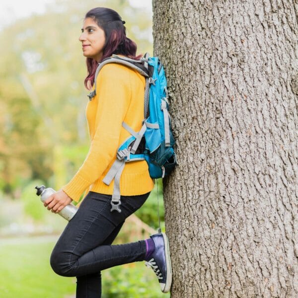 young lady stands against a tree scaled