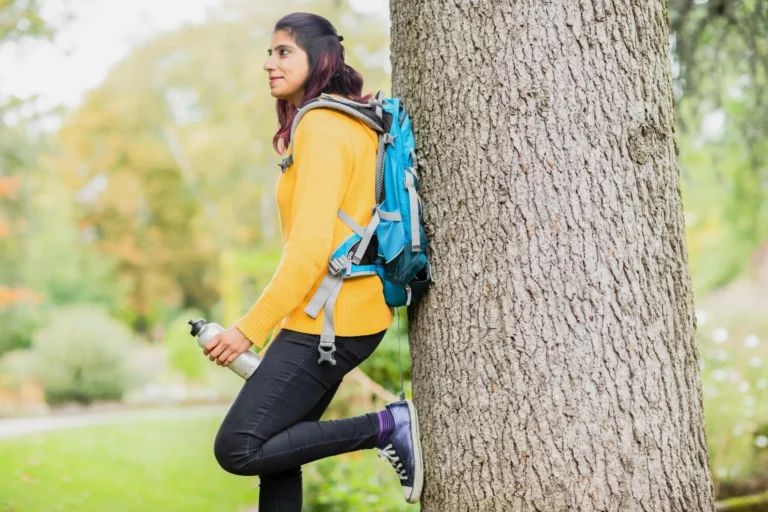 young lady stands against a tree scaled