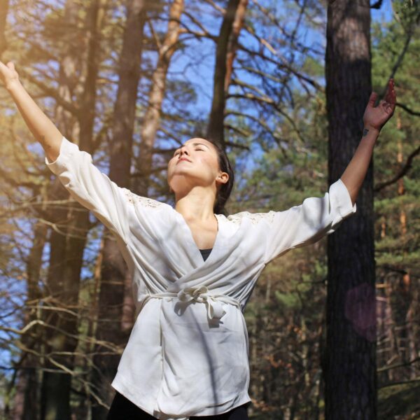 young woman dances amongst trees