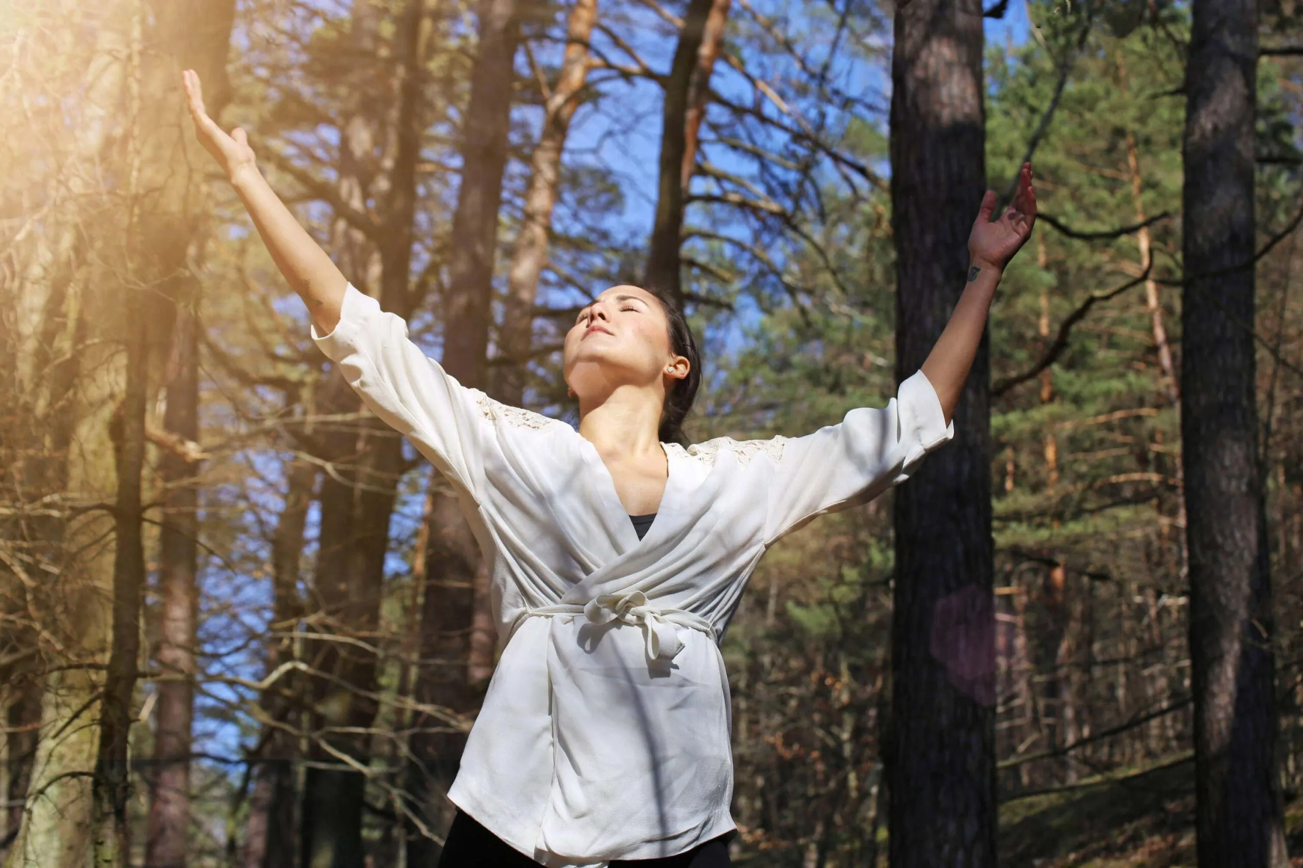 young woman dances amongst trees