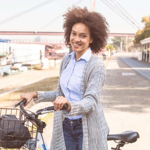 young woman walks along pushing her bicycle scaled