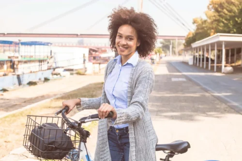 young woman walks along pushing her bicycle scaled