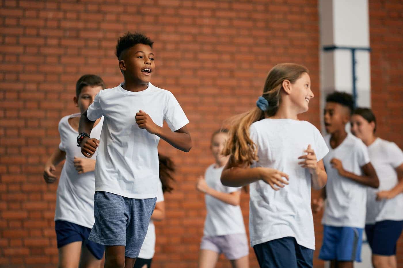 Group of school children run during physical education class at school gym