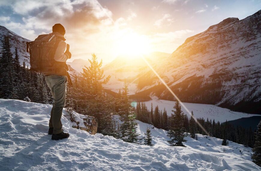 mountain hiker looks out over snowy mountains