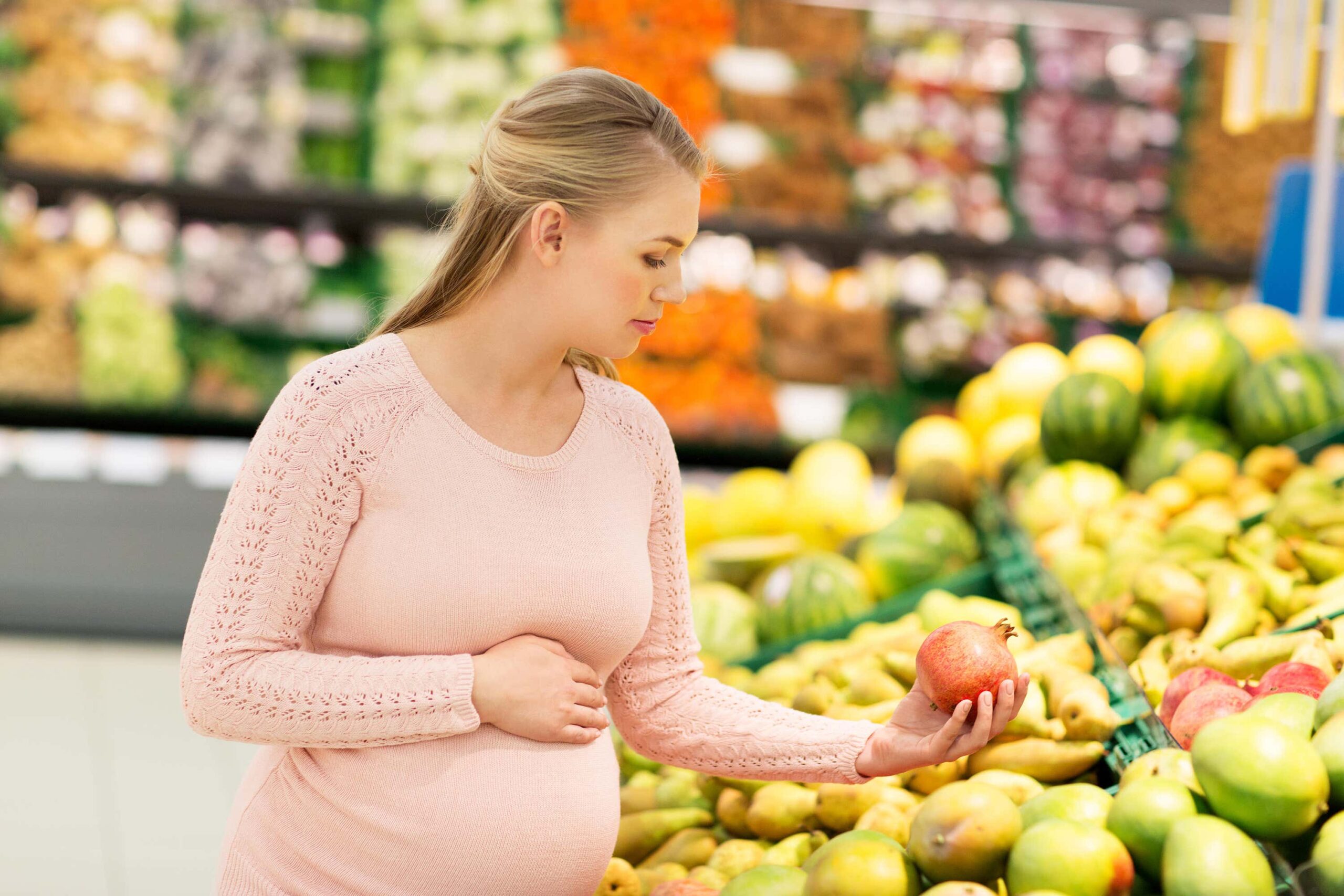 Pregnant woman looks at fruit scaled