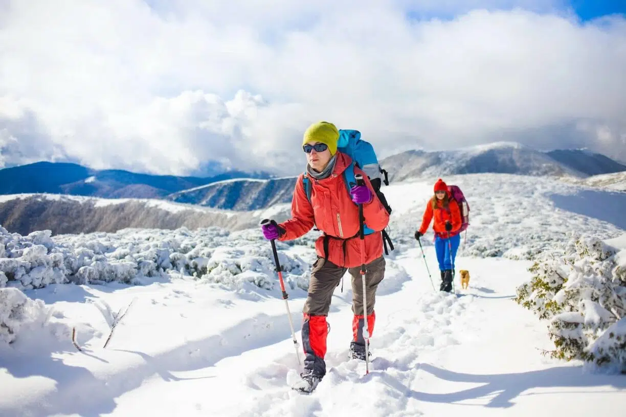 Two female hikers climb mountains covered in snow