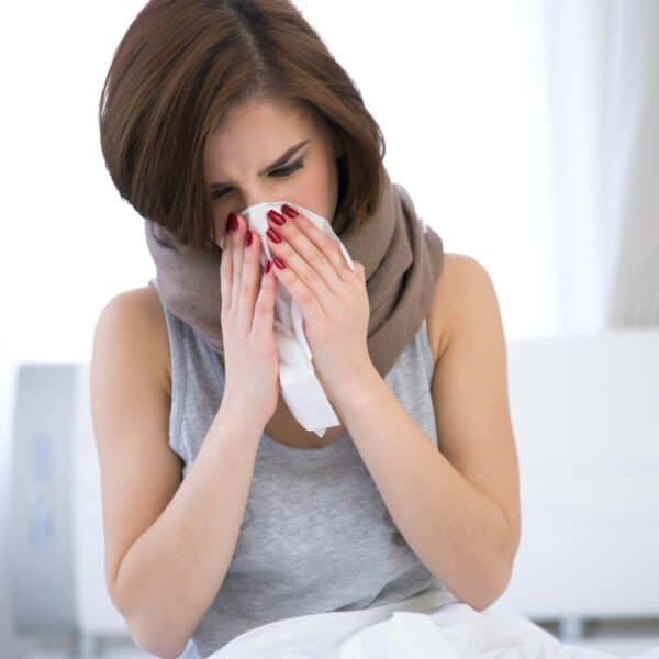 woman blows nose into tissue scaled