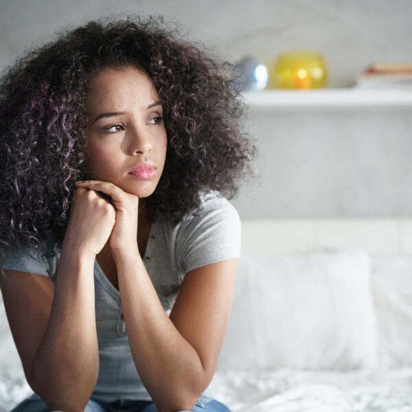 woman sits anxiously on bed