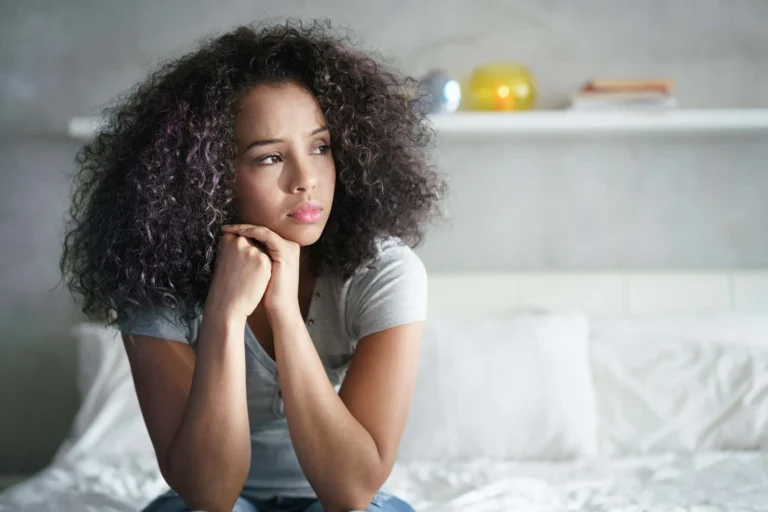 woman sits anxiously on bed