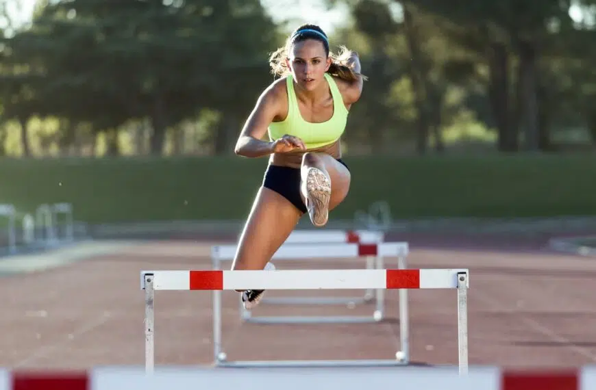 young athlete jumping over a hurdle during training