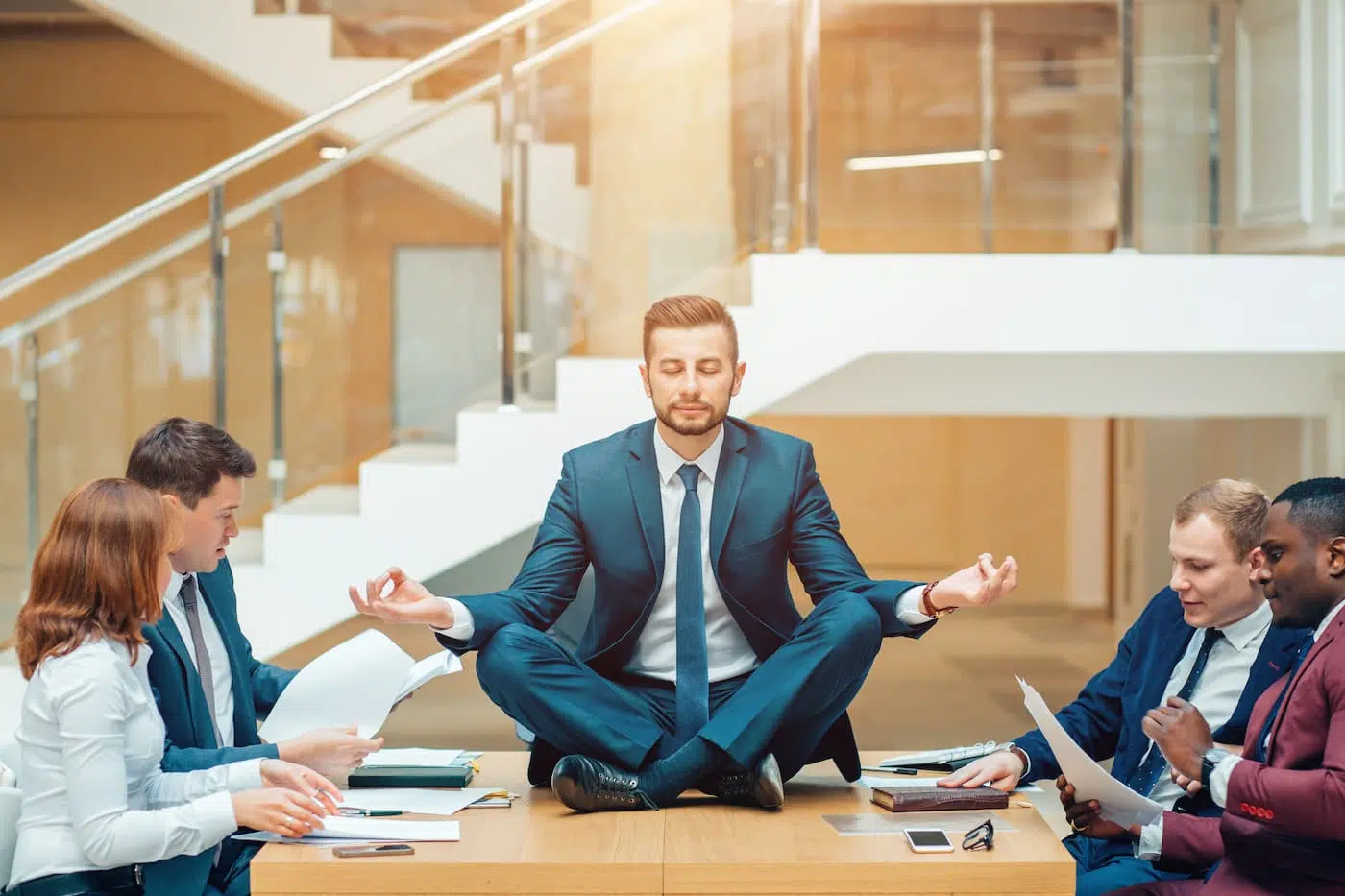 Businessman wearing a suit doing yoga on the table
