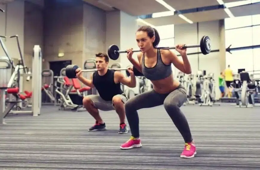 gym couple lift barbells on shoulders