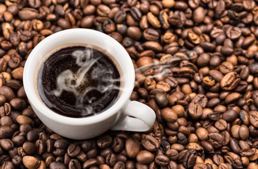 hot coffee in cup surrounded by coffee beans